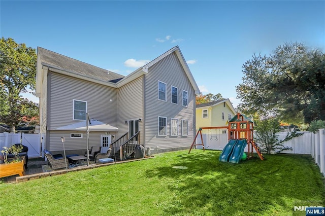 rear view of property featuring entry steps, a playground, a yard, and a fenced backyard