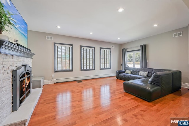 living room featuring visible vents, light wood-style floors, and a baseboard radiator