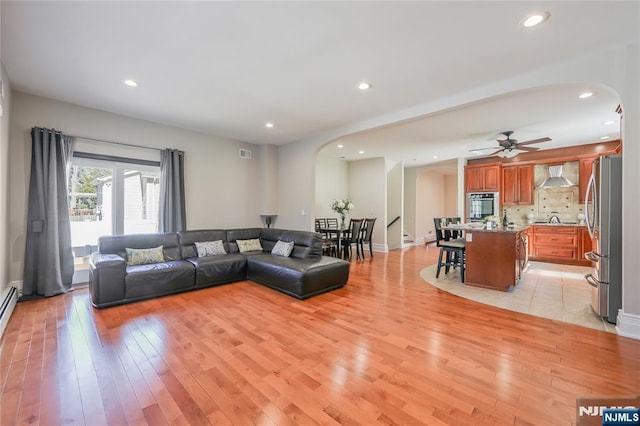 living room featuring recessed lighting, light wood-type flooring, and arched walkways