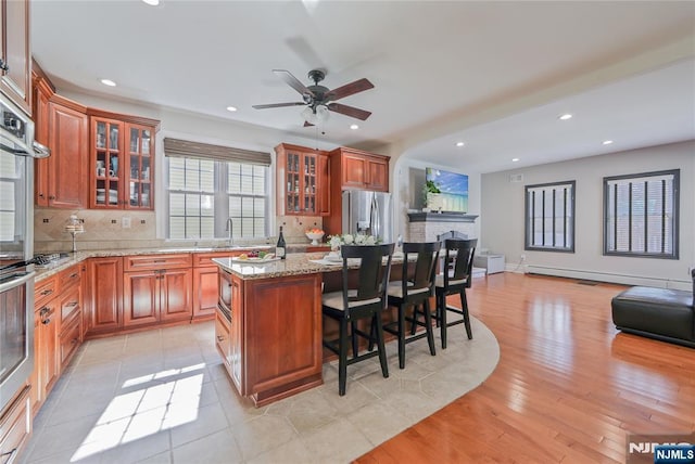 kitchen featuring tasteful backsplash, a center island, open floor plan, a breakfast bar, and stainless steel appliances