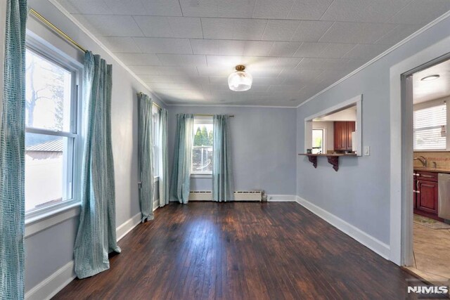 unfurnished room featuring a baseboard heating unit, dark wood-type flooring, baseboards, and ornamental molding