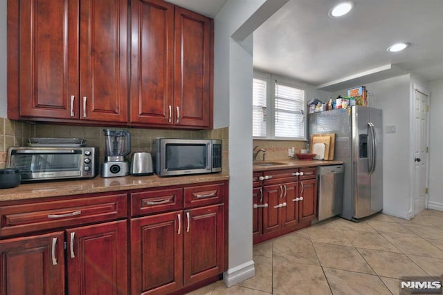 kitchen featuring backsplash, a toaster, reddish brown cabinets, and stainless steel appliances