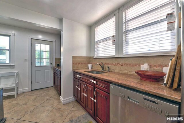 kitchen featuring light tile patterned floors, backsplash, a sink, dishwasher, and reddish brown cabinets