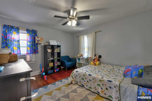 bedroom with multiple windows, baseboards, ceiling fan, and wood finished floors