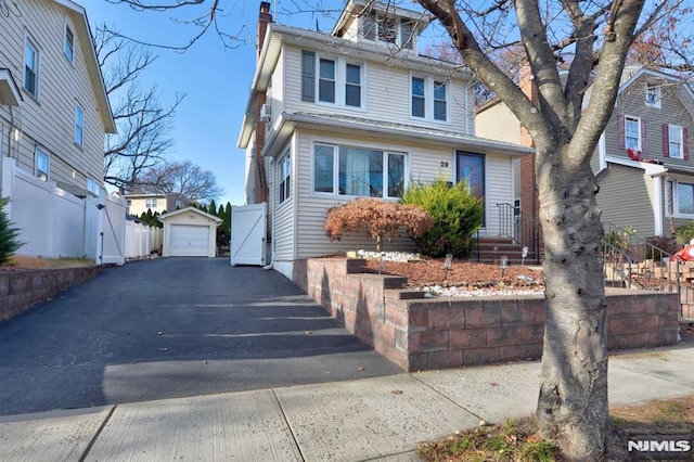 american foursquare style home with a detached garage, fence, aphalt driveway, a chimney, and an outdoor structure