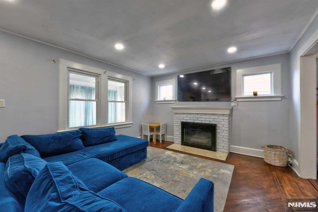 living room featuring crown molding, baseboards, recessed lighting, a fireplace, and wood finished floors