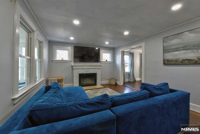 living room with a brick fireplace, recessed lighting, wood finished floors, and baseboards