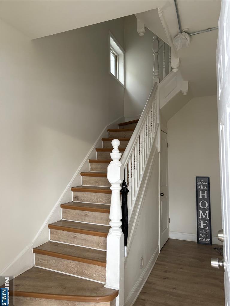 staircase featuring wood finished floors and baseboards