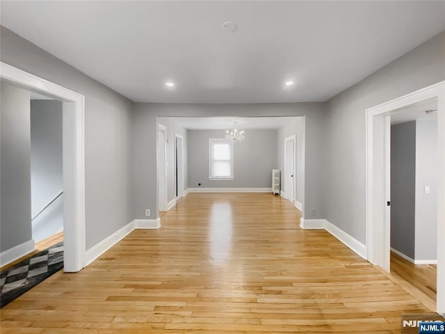 interior space featuring baseboards, radiator, an inviting chandelier, and light wood finished floors