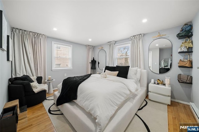 bedroom with recessed lighting, a baseboard heating unit, baseboards, and wood finished floors