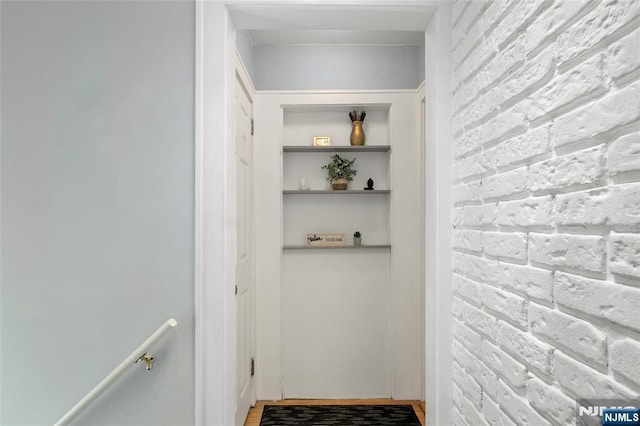 hallway with an upstairs landing and brick wall