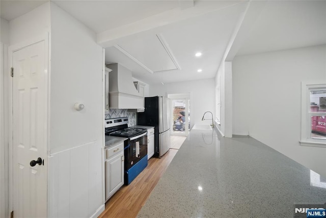 kitchen with decorative backsplash, light stone countertops, stainless steel appliances, and premium range hood