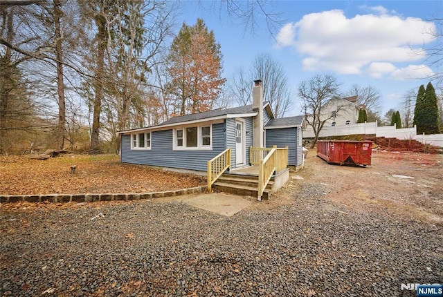 view of front of property with a chimney, gravel driveway, and fence