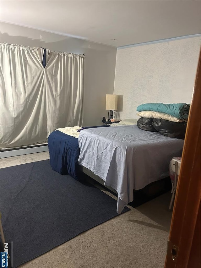 bedroom with a baseboard heating unit and carpet flooring