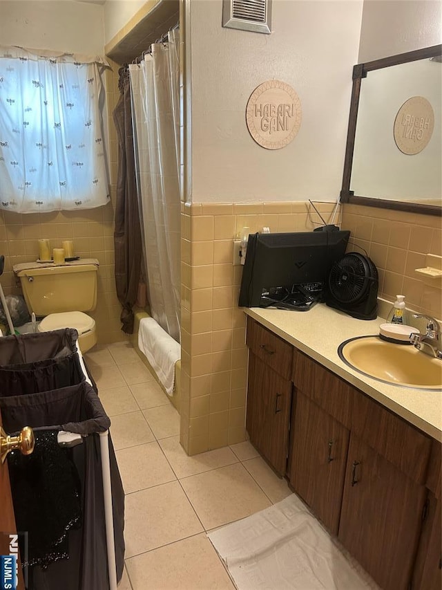 bathroom featuring tile patterned flooring, visible vents, toilet, and tile walls