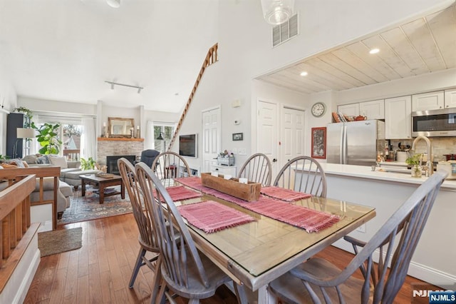 dining room with visible vents, dark wood-style floors, recessed lighting, a high ceiling, and a fireplace