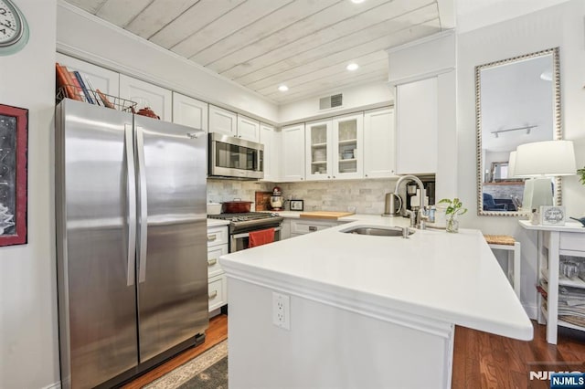 kitchen featuring visible vents, a peninsula, a sink, white cabinets, and appliances with stainless steel finishes