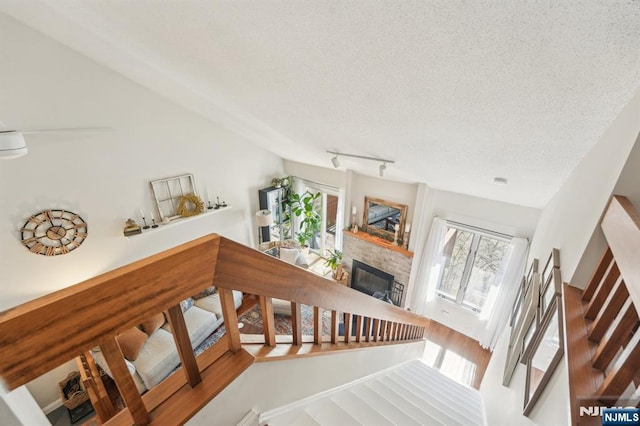 staircase featuring wood finished floors, a textured ceiling, a glass covered fireplace, and rail lighting