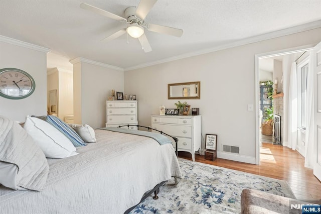 bedroom featuring visible vents, a ceiling fan, wood finished floors, crown molding, and baseboards