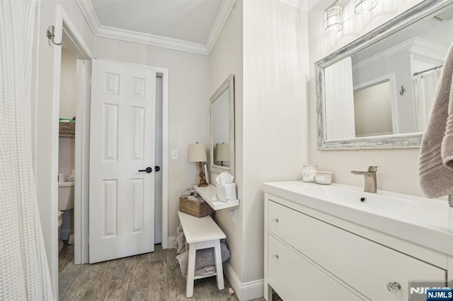 bathroom featuring toilet, wood finished floors, vanity, and ornamental molding