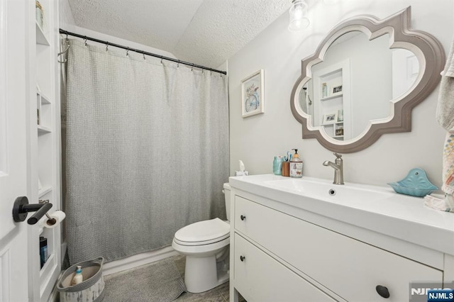 bathroom featuring vanity, a shower with shower curtain, toilet, and a textured ceiling