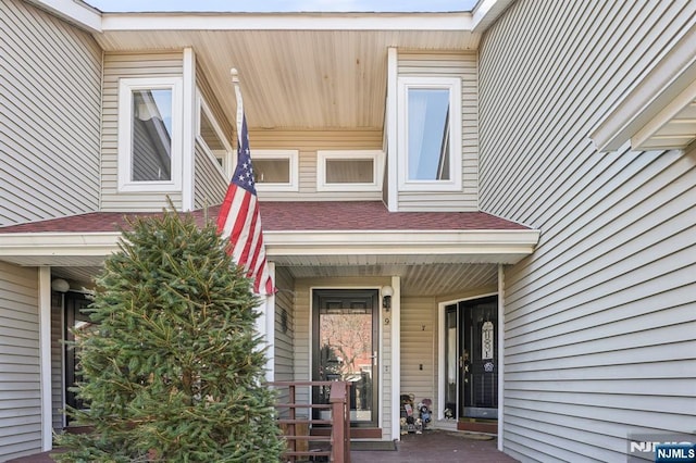 property entrance featuring a porch and roof with shingles