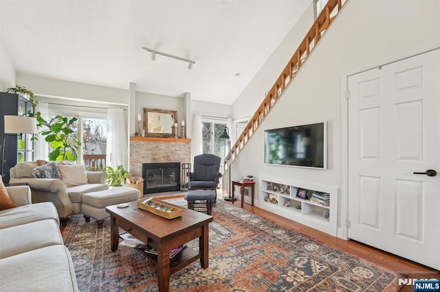 living area with baseboards, plenty of natural light, wood finished floors, and a fireplace with flush hearth