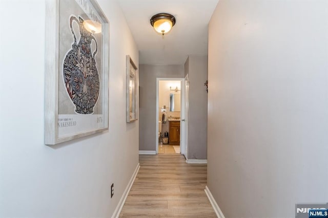 corridor with light wood-type flooring and baseboards