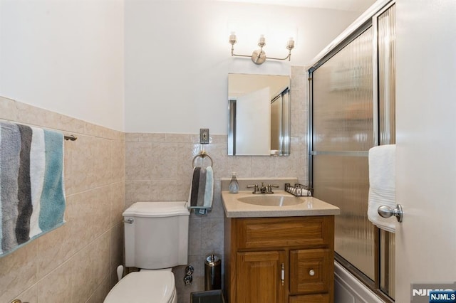 bathroom with vanity, tile walls, and toilet