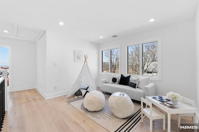 living room featuring visible vents, baseboards, attic access, recessed lighting, and light wood-style flooring