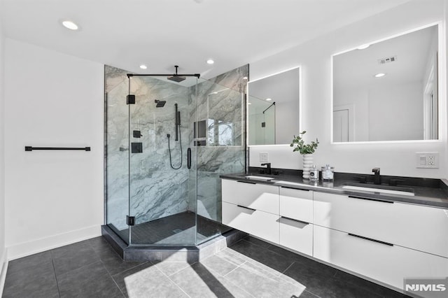 full bath featuring double vanity, a stall shower, visible vents, and a sink