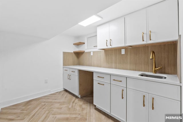 kitchen featuring a sink, open shelves, light countertops, and white cabinetry