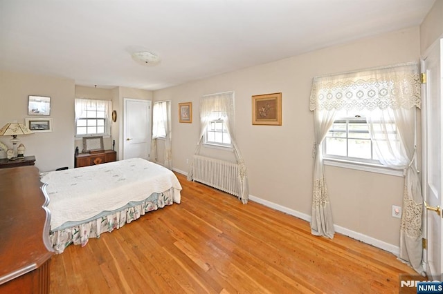 bedroom with baseboards, light wood-style flooring, and radiator heating unit