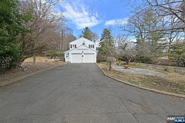 view of front of property featuring an attached garage, driveway, and fence