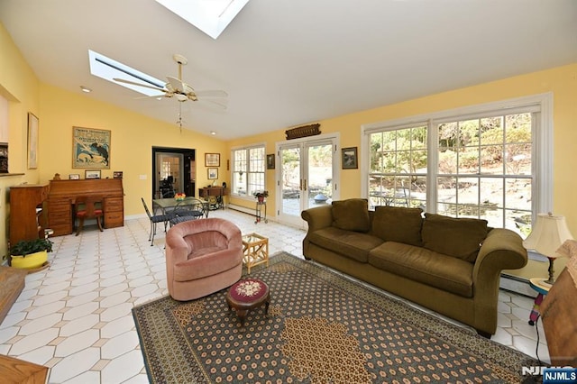 living area featuring vaulted ceiling with skylight, a baseboard heating unit, and a ceiling fan