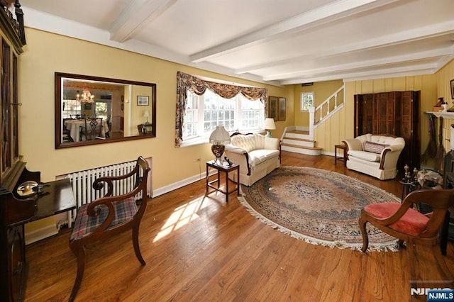 living room with baseboards, stairway, radiator heating unit, beam ceiling, and wood finished floors