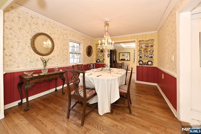 dining area with a wainscoted wall, an inviting chandelier, crown molding, and wallpapered walls