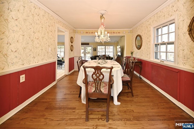 dining room with wallpapered walls, wood finished floors, a wainscoted wall, and a chandelier