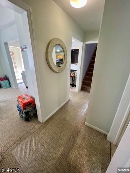 hall featuring stairs, carpet, and baseboards