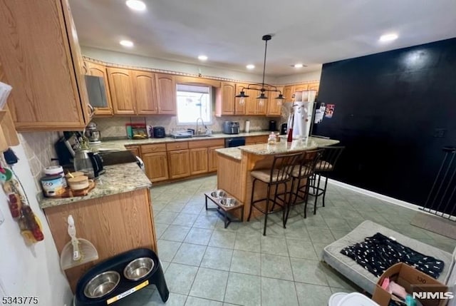 kitchen with a sink, decorative light fixtures, a kitchen breakfast bar, a kitchen island, and decorative backsplash