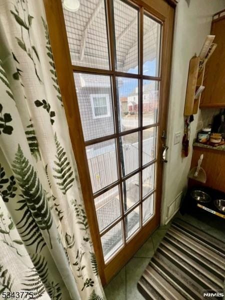 doorway featuring a healthy amount of sunlight and tile patterned flooring