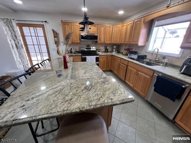 kitchen featuring tasteful backsplash, a center island, appliances with stainless steel finishes, a breakfast bar area, and light stone countertops