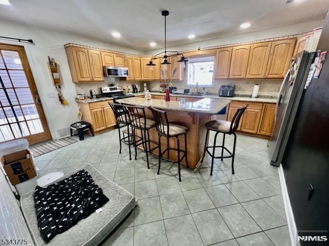 kitchen featuring a sink, light tile patterned flooring, a kitchen island, and stainless steel appliances