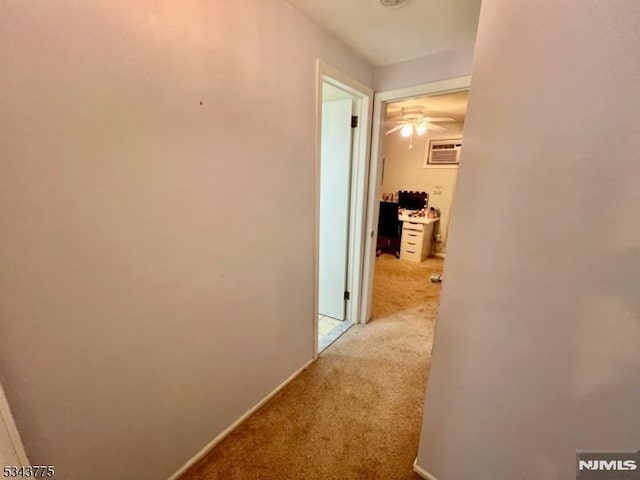 hall featuring baseboards, carpet, and a wall unit AC