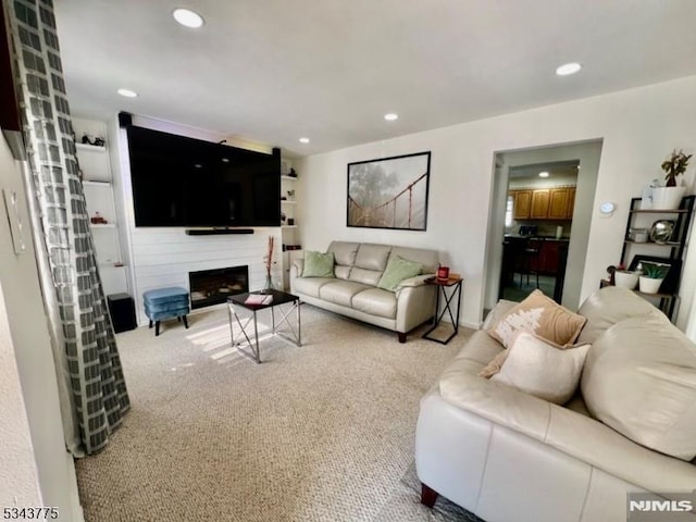 carpeted living area with recessed lighting and a fireplace