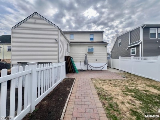 rear view of property featuring a fenced backyard and a patio area