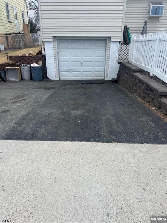 garage with aphalt driveway and fence