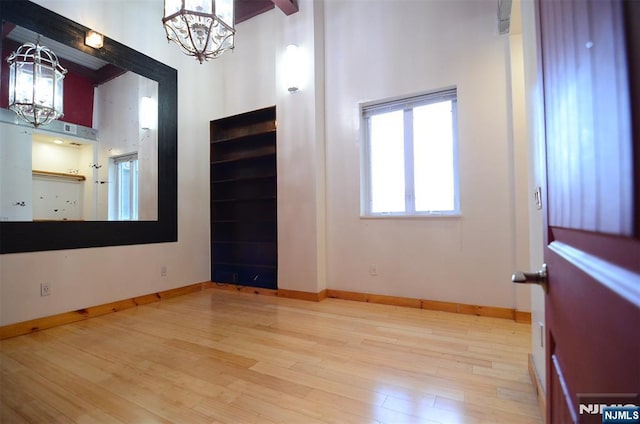 75 Liberty Ave Unit B23, Jersey City, NJ 07306 - unfurnished room with a notable chandelier, baseboards, and wood finished floors