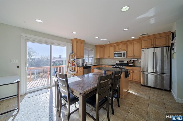 kitchen with a sink, dark countertops, recessed lighting, appliances with stainless steel finishes, and decorative backsplash