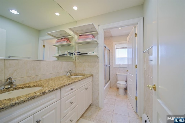 bathroom with tile walls, toilet, a baseboard heating unit, and a sink